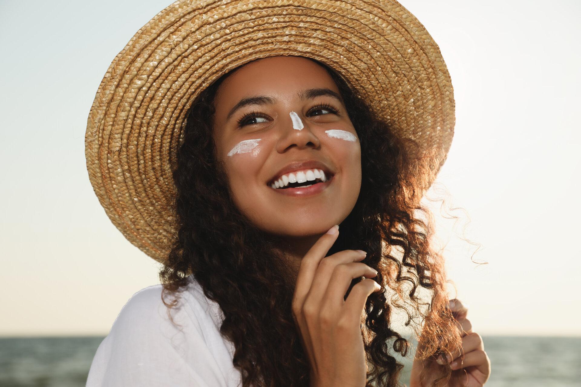 Glückliche afroamerikanische Frau mit Sonnenschutzcreme im Gesicht 