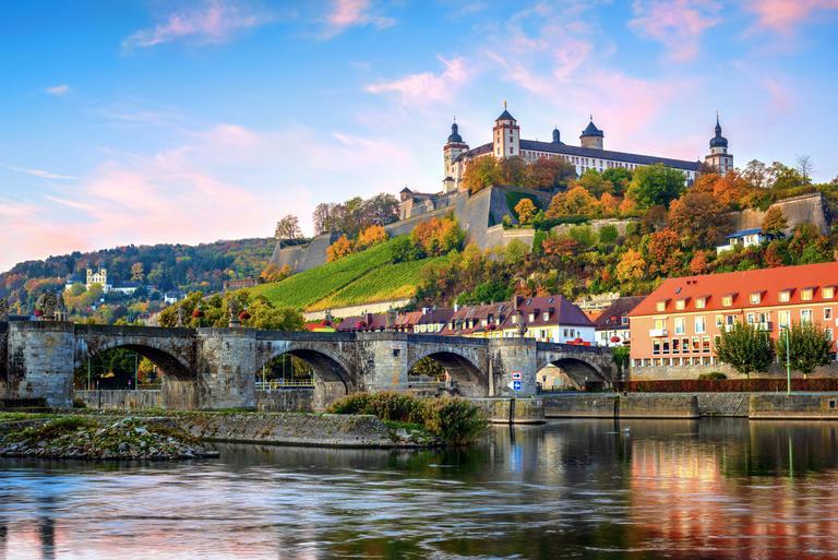 Würzburg, Bayern, Deutschland, Blick auf die Festung Marienberg und die Alte Mainbrücke bei farbigem Sonnenaufgang