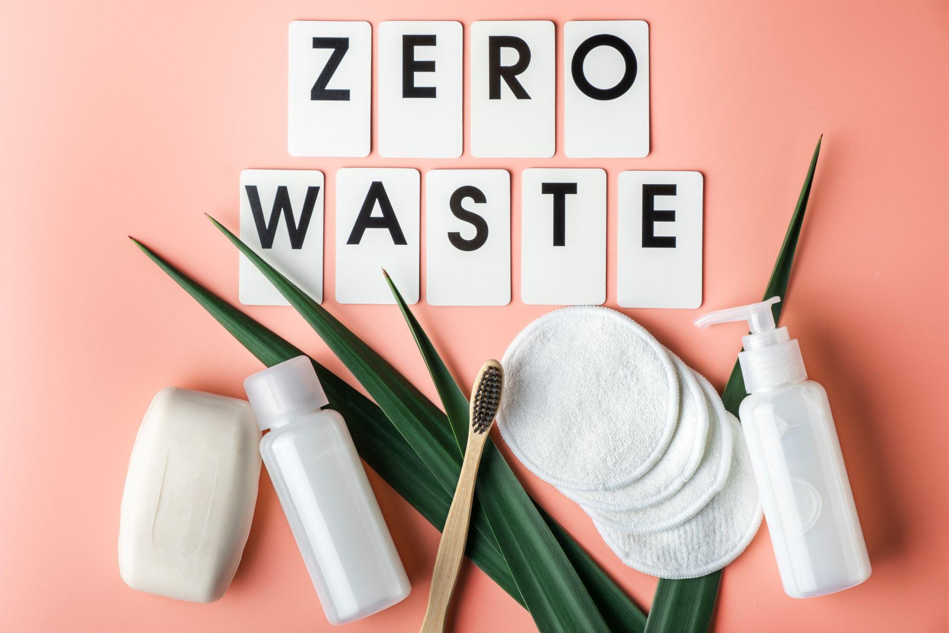 Zero Waste Pflegeprodukte auf einem rosafarbenen Hintergrund. Enthalten sind eine Zahnbürste aus Bambus, wiederverwendbare Wattepads und plastikfreie Verpackungen. Perfekt für einen nachhaltigen Lebensstil.