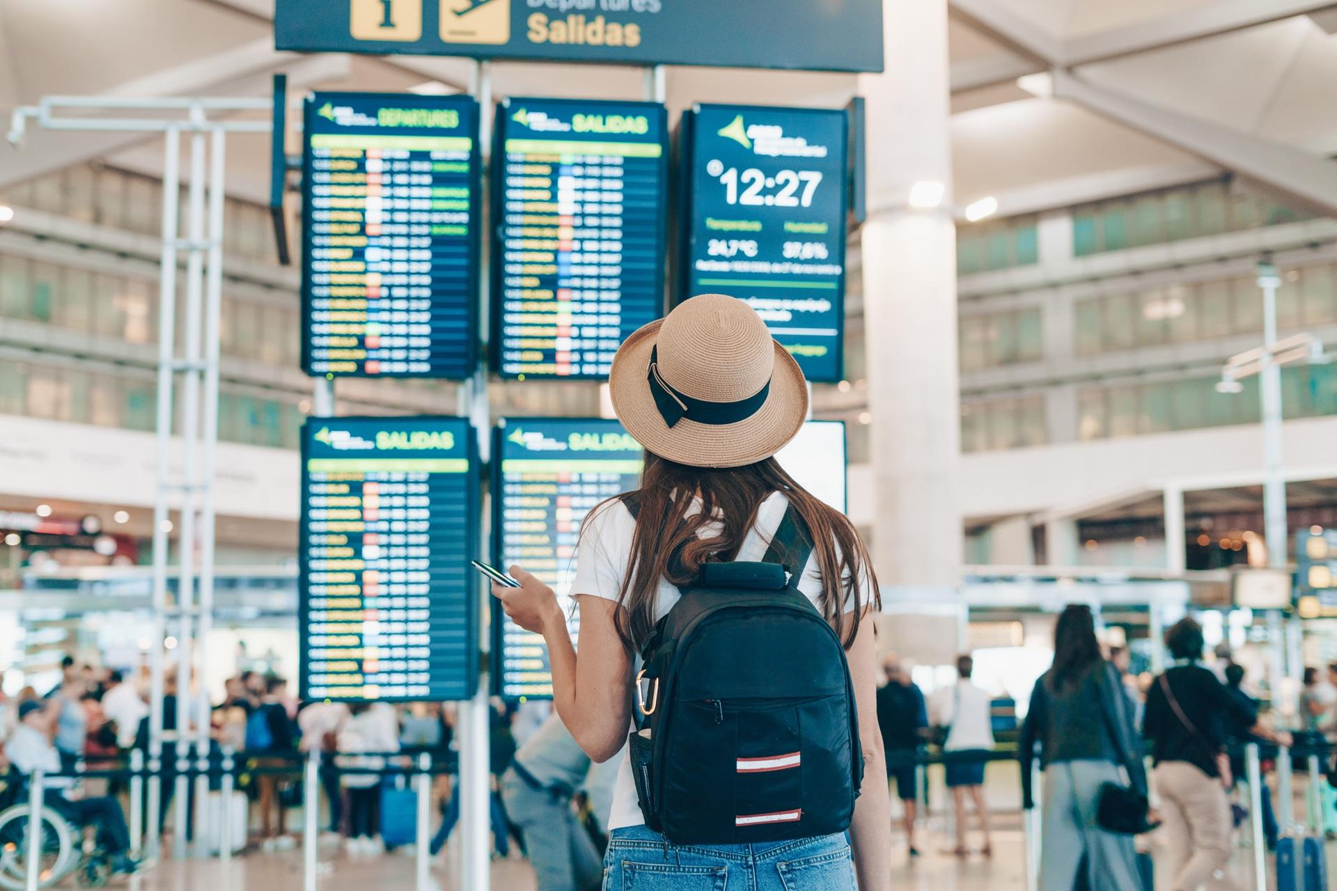 Frau mit Rucksack blickt auf Abflugtafel | Flughafen Shuttle Frankfurt