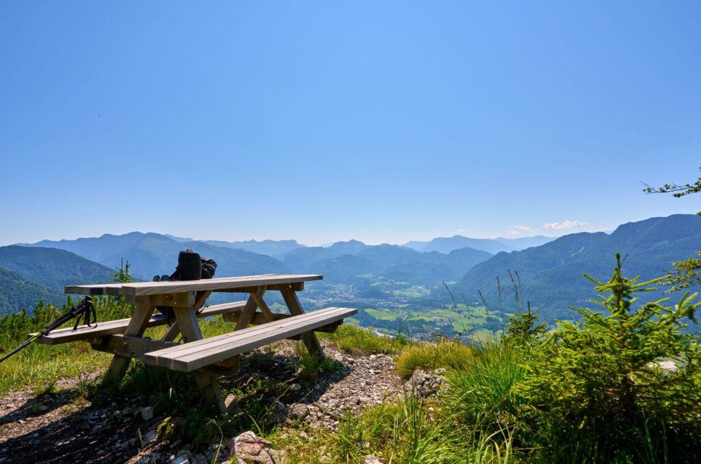 Picknickbank mit Rucksack auf Bergplateau, Blick über grünes Tal und Alpenpanorama nahe Hotel Kleinarl