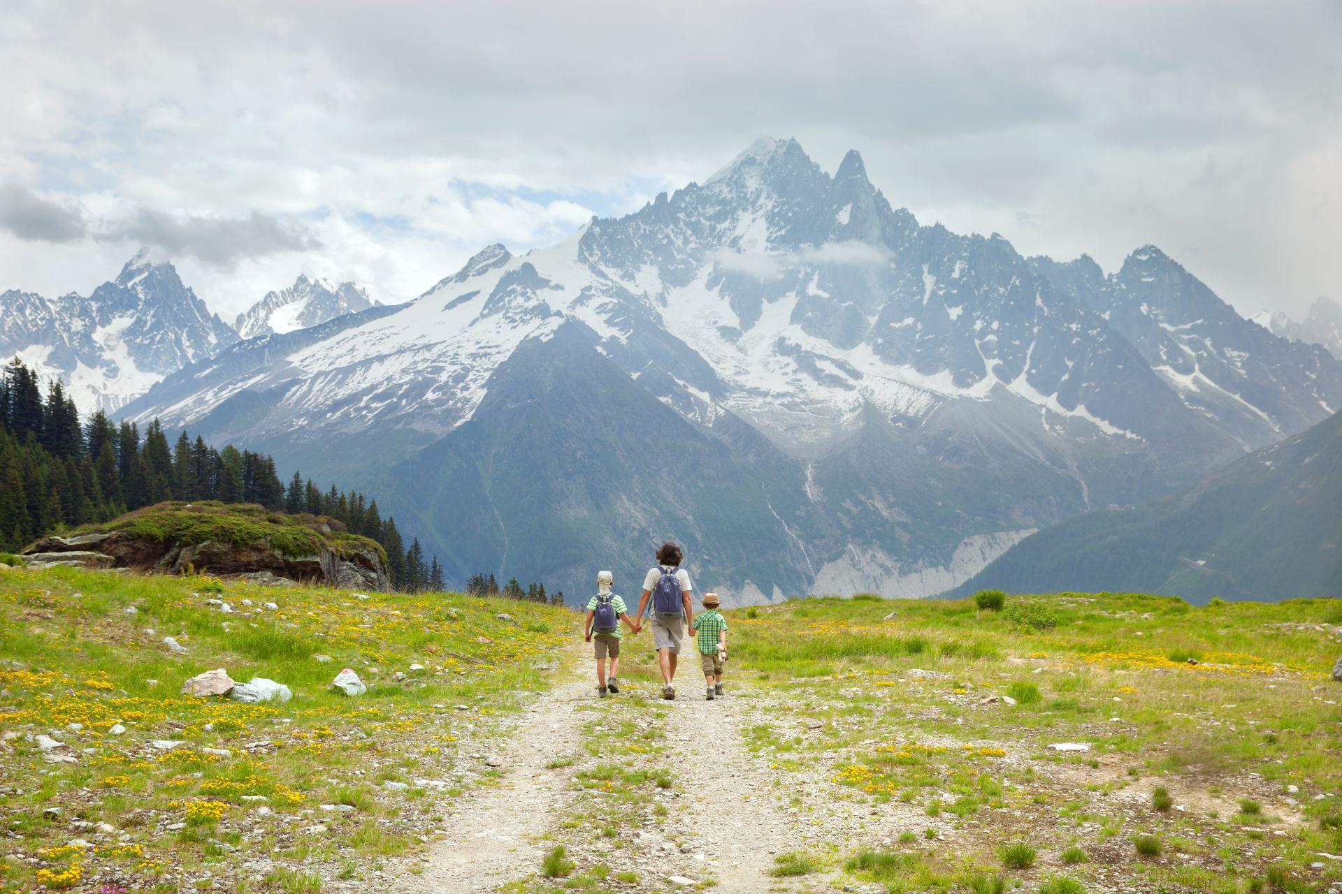 Familie wandert auf Almwiese mit Blick auf verschneite Alpen, Naturerlebnis rund um Hotel Kleinarl